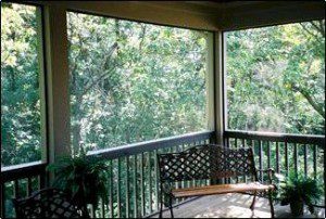 A screened in porch with a bench and trees.